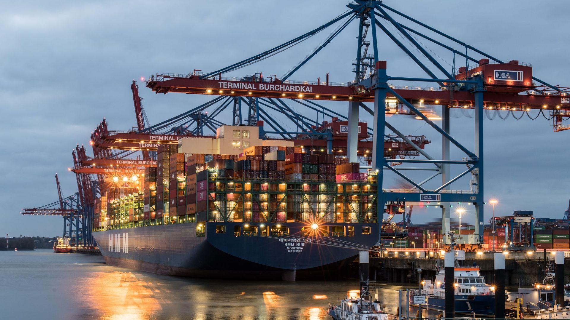 Container terminal at dusk with a vessel alongside under gantry cranes